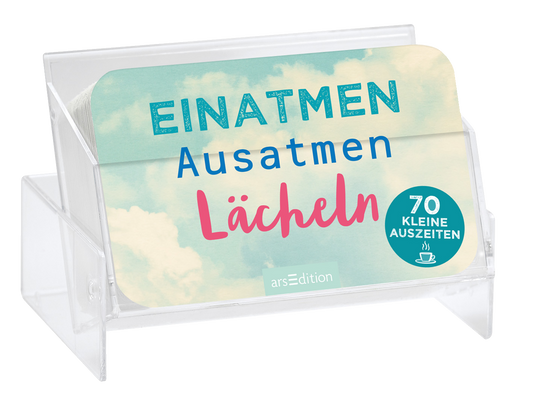 Auf dem Buchcover sind die Worte „EINATMEN“, „AUSATMEN“ und „LÄCHELN“ prominent in verschiedenen Farben angeordnet. Die Schrift „EINATMEN“ ist in einem glitzernden Blauton gehalten, während „AUSATMEN“ in einem kräftigen Blau und „LÄCHELN“ in einem leuchtenden Pink erscheint. Der Hintergrund zeigt eine sanfte, hellblaue Himmelslandschaft mit Wolken. Oben rechts befindet sich ein runder Button mit der Aufschrift „70 KLEINE AUSZEITEN“. Ganz unten mittig steht der...