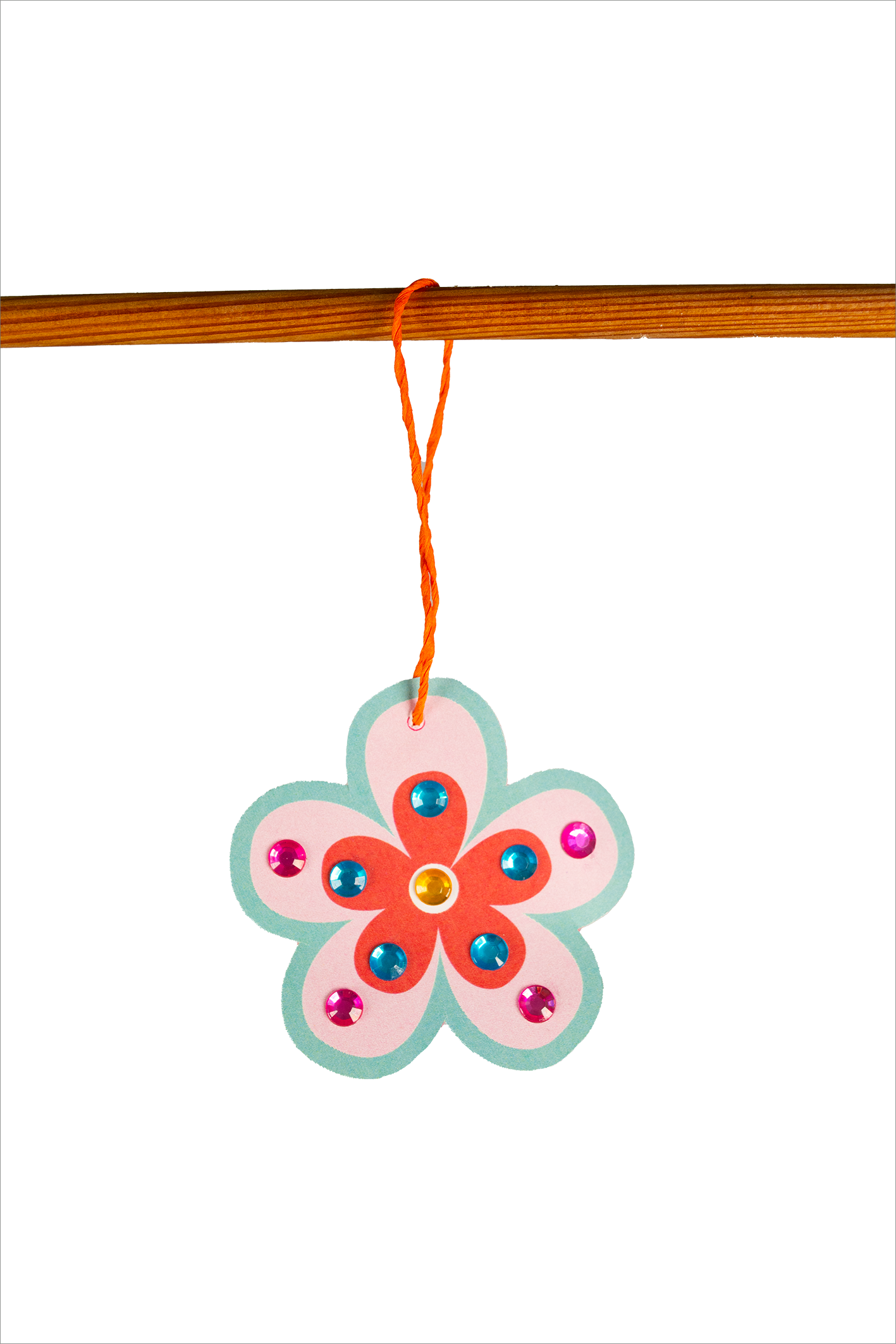 Gezeigt wird eine Innen- oder Zusatzansicht von „Diamant-Oster-Anhänger“. Der Anhänger hat die Form einer Blume und besteht aus mehreren Farben, einschließlich einem hellblauen Rand und einer roten Blütenmitte. Auf der Blüte sind glänzende, farbige Steine in Blau, Pink und Gelb angebracht, die einen festlichen Eindruck vermitteln. Am oberen Ende ist ein orangefarbener Faden befestigt, der den Anhänger zum Aufhängen nutzt.