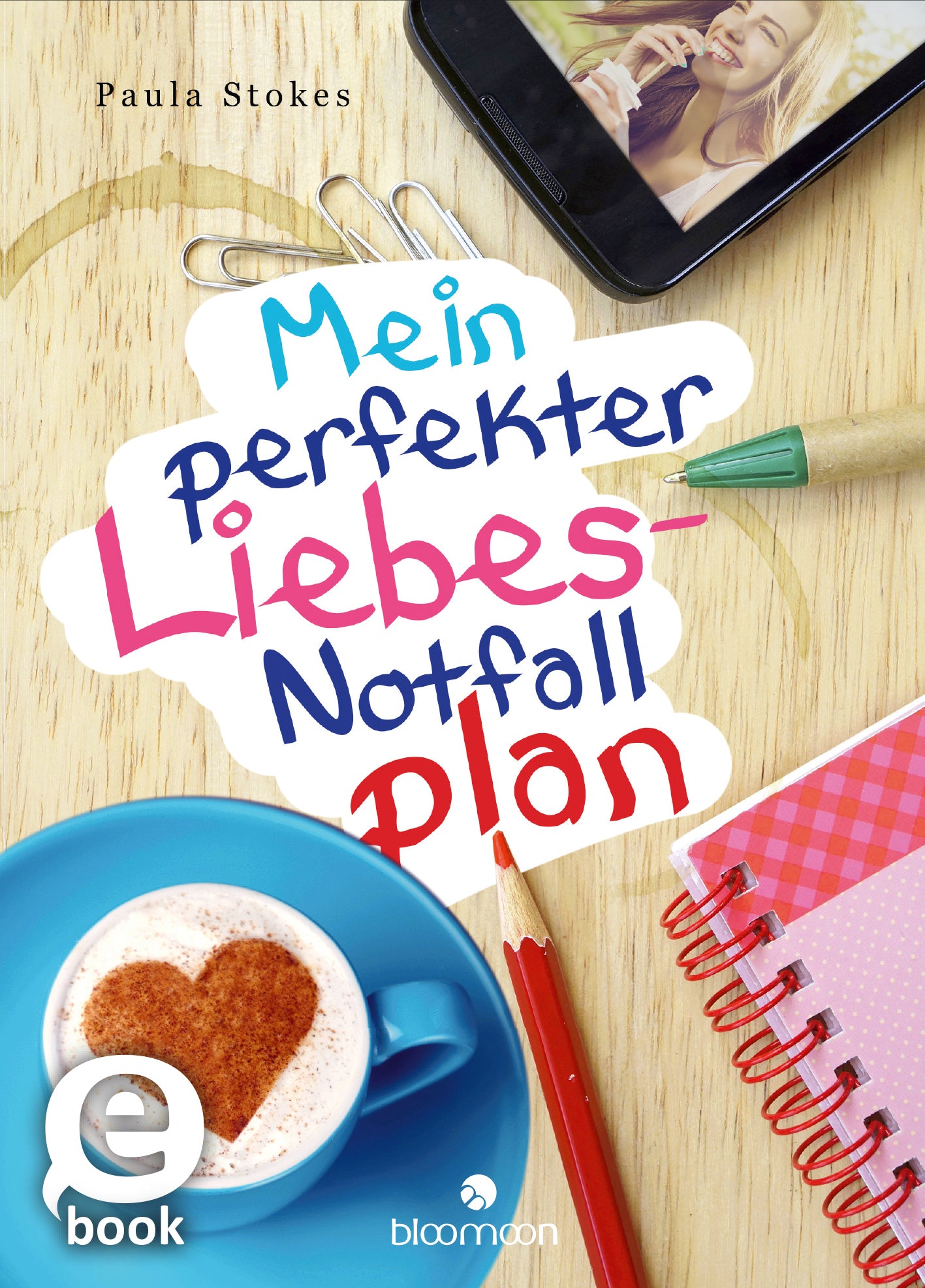 Das Buchcover zeigt einen hellen Holzuntergrund mit einem großen, bunten Schriftzug, der den Titel „Mein perfekter Liebes-Notfall-Plan“ in lebhaften Farben präsentiert. Der Text ist fröhlich gestaltet und hebt sich mit einer Mischung aus Blau, Rot und Pink hervor. Im oberen Bereich ist ein lächelndes Mädchen zu sehen, während im unteren Teil eine Tasse mit Herz-Kakaopulver und einige Schreibutensilien platziert sind. Oben links steht der Name der Autorin, Paula Stokes. Ganz unten...