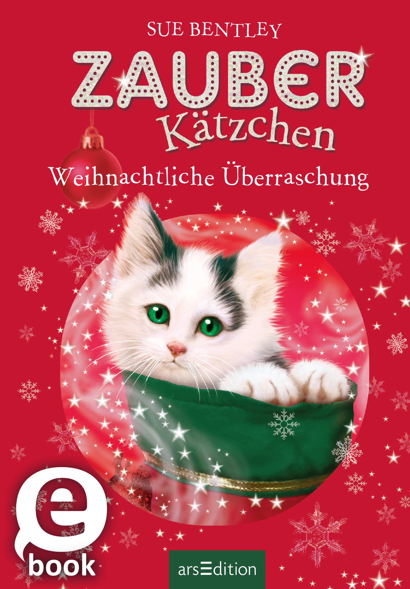 Das Buchcover zeigt ein süßes, weißes Kätzchen mit grünen Augen, das in einem grünen Behälter sitzt. Der Hintergrund ist in einem festlichen Rotton gehalten und mit zarten, weißen Schneeflocken verziert. Oben steht in verspielter Typografie „ZAUBER Kätzchen“ und darunter in schlichter Schrift „Weihnachtliche Überraschung“. Ein SPIEGEL-Bestseller-Button ist vorhanden. Ganz unten mittig steht der Logoschriftzug von arsEdition.