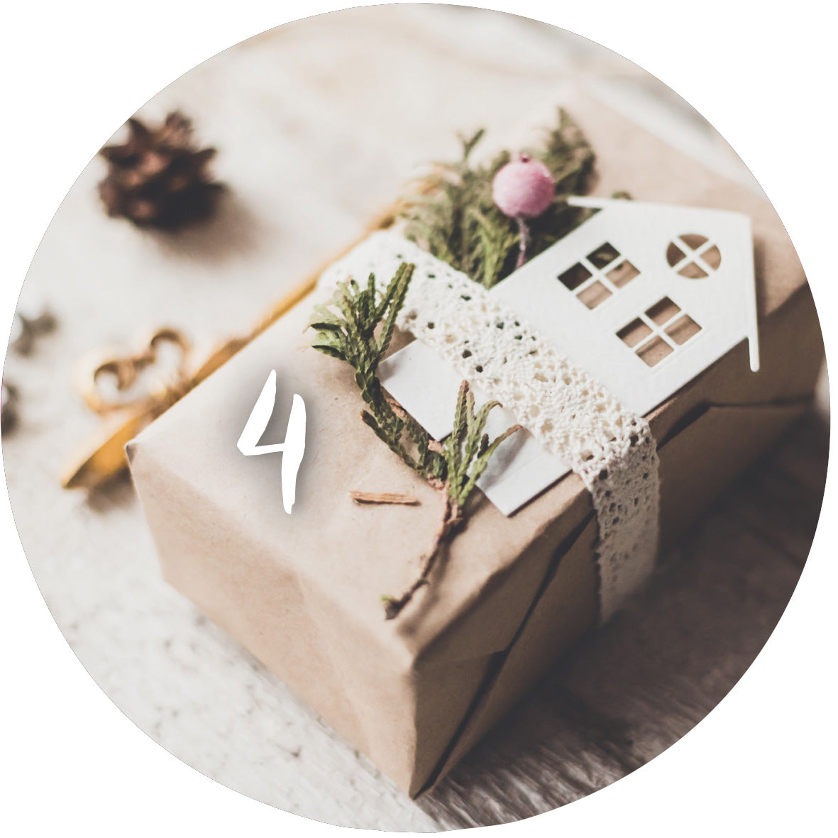 Gezeigt wird eine Innen- oder Zusatzansicht von „Adventskalender in der Dose. 24 Momente der Achtsamkeit“. Die Abbildung zeigt ein liebevoll verpacktes Geschenk in Kraftpapier mit einer dekorativen Schleife aus Spitze. An dem Geschenk befindet sich eine kleine, weiße Papphaus-Form und frische grüne Zweige mit einer rosa Kuller. Die Zahl „4“ in geschwungener, weißer Schrift unterstreicht das weihnachtliche Ambiente. Die Farbpalette ist warm und einladend, ideal für die Adventszeit.