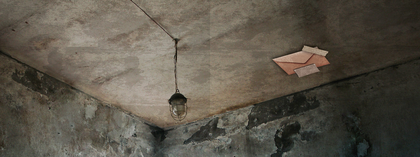 Gezeigt wird eine Innenansicht von „Escape Room. Der erste Escape-Adventskalender“. Der Raum wirkt dunkel und verwahrlost mit einem rauen, grauen Betonboden und einer schmutzigen Decke. Eine hängende, vintage Lampe beleuchtet den Raum spärlich. An der Decke ist ein brauner Umschlag zu sehen, der mit Klebeband angeheftet ist. Die Atmosphäre ist geheimnisvoll und düster.