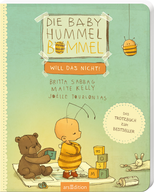 Das Buchcover zeigt eine kinderfreundliche Illustration in sanften Pastellfarben. Im Mittelpunkt steht die couragierte Hummelfigur, die in einem Streifen-Outfit dargestellt ist. Neben ihr sitzt ein Bär, der mit bunten Bauklötzen spielt. Der Titel „Die Baby Hummel Bommel – Will das nicht!“ prangt in großen, freundlichen Buchstaben oben. Die Urheber Britta Sabbag, Maite Kelly und Joëlle Tourlonias sind darunter in einer modernen Schrift aufgeführt. Oben links ist ein...