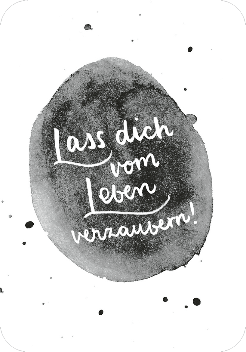 Gezeigt wird eine Innen- oder Zusatzansicht von „Glücksmantras für die Handtasche“. Im Mittelpunkt steht ein grafisches, ovales Element in Grau- und Schwarztönen, das einem Aquarell ähnlich ist. Darin befindet sich die handgeschriebene, weiße Schrift mit der Botschaft „Lass dich vom Leben verzaubern!“. Die verspielte Typografie vermittelt Leichtigkeit und Inspiration, während der Hintergrund eine sanfte und einladende Atmosphäre schafft.