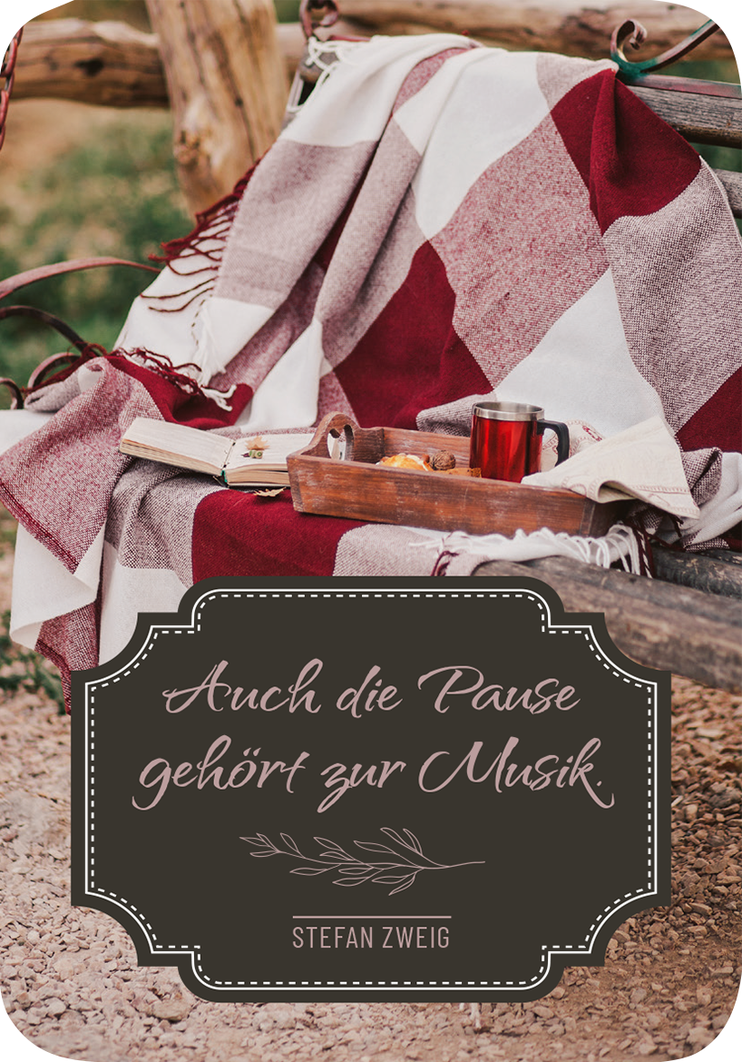 Gezeigt wird eine Innen- oder Zusatzansicht von „Weisheiten für die Seele“. Auf einem rustikalen Holzstuhl liegt eine gemusterte Decke in Rot- und Grautönen. Neben der Decke steht eine kleine Holzschale mit Snacks und einem Getränk in einem Glas. Im Vordergrund befindet sich ein elegantes, geschwungenes Textfeld in dunklem Braun, auf dem in einer verspielten Schrift „Auch die Pause gehört zur Musik“ und darunter „Stefan Zweig“ zu lesen ist.