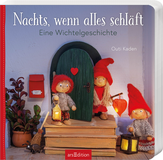 Auf dem Buchcover „Nachts, wenn alles schläft“ ist eine zauberhafte Wichtelgeschichte abgebildet. Drei fröhliche Wichtel mit roten Mützen stehen vor einer hübschen, grünen Tür, die ein kleines rotes Herz hat. Neben ihnen steht ein Wichtel mit einer Laterne. Hinter ihnen sieht man eine rote Postbox. Der Hintergrund ist sanft und hell gehalten. Der Titel ist in großen, weißen Buchstaben geschrieben. Ganz unten mittig steht der Logoschriftzug von arsEdition.