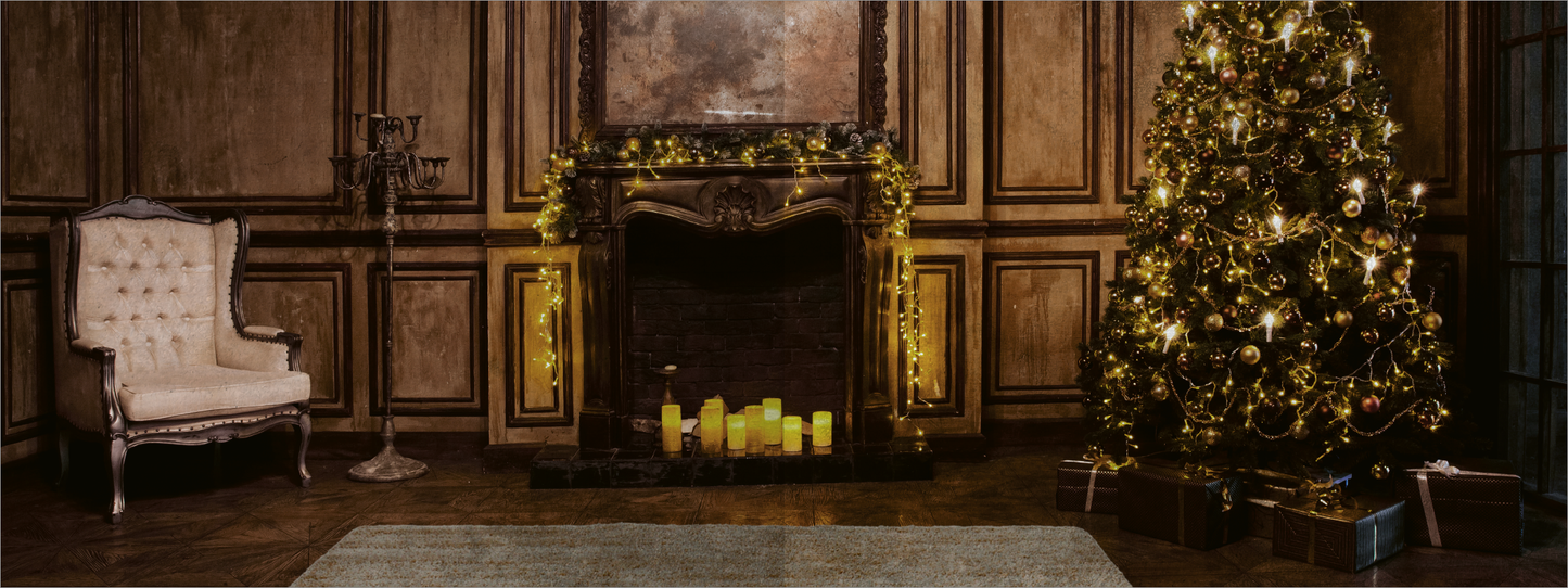 Gezeigt wird eine Innen- oder Zusatzansicht von „Ein Toter zur Bescherung“. Der Raum ist elegant mit Holzwänden und einem großen Weihnachtsbaum geschmückt, der mit goldenen Ornamenten und Lichtern versehen ist. Im Vordergrund steht ein gemütlicher, weißer Sessel. Der Kamin ist mit Kerzen und goldener Dekoration geschmückt. Insgesamt dominieren warme, goldene und braune Farbtöne die harmonische Atmosphäre des Raumes.