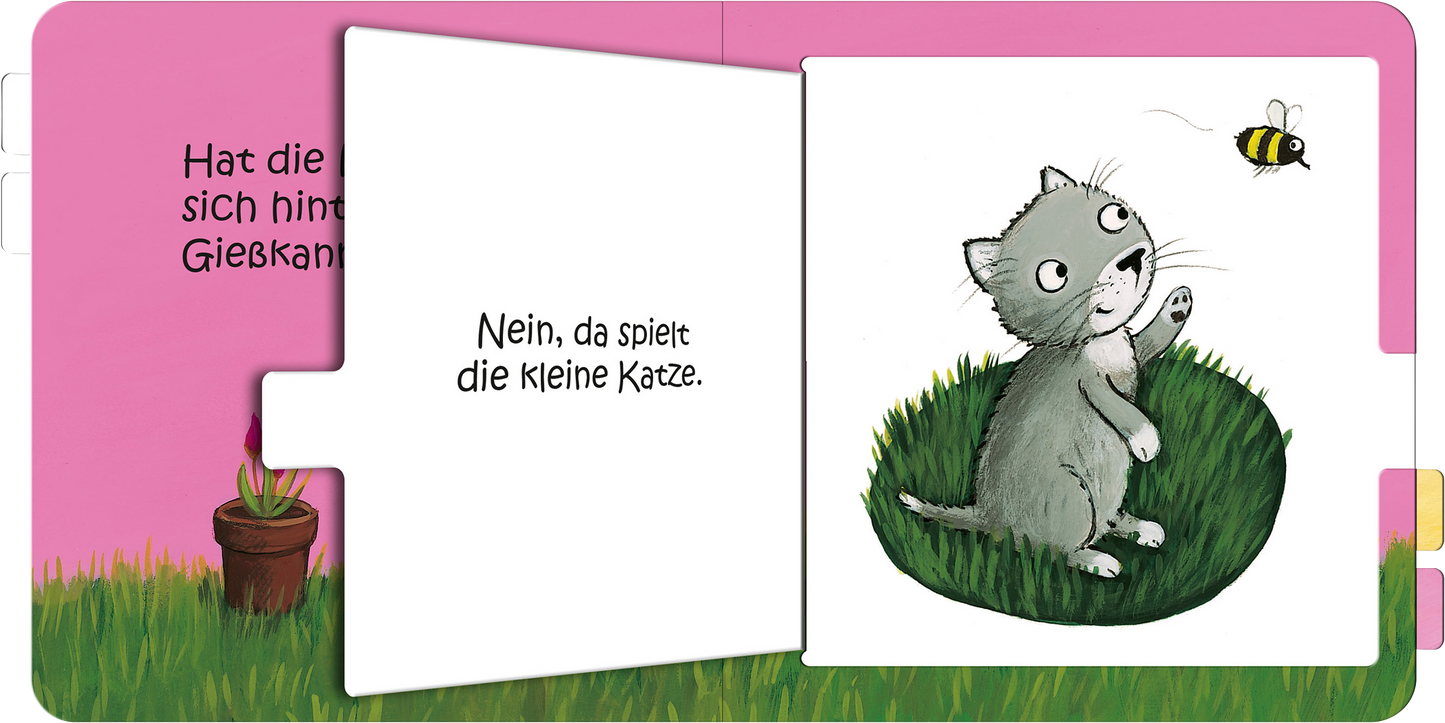 Gezeigt wird eine Innen- oder Zusatzansicht von „Wo bist du, kleine Maus?“. Die Seite zeigt eine niedliche, graue Katze auf grünem Gras, die neugierig einen kleinen Schmetterling beobachtet. Im Hintergrund ist eine rosa Wand mit einer Blumen-Illustration. Der Text „Nein, da spielt die kleine Katze.“ steht in einer klaren, runden Schriftart, die gut leserlich ist. Farbkontraste unterstützen die visuelle Ansprache und machen die Seite freundlich und ansprechend.