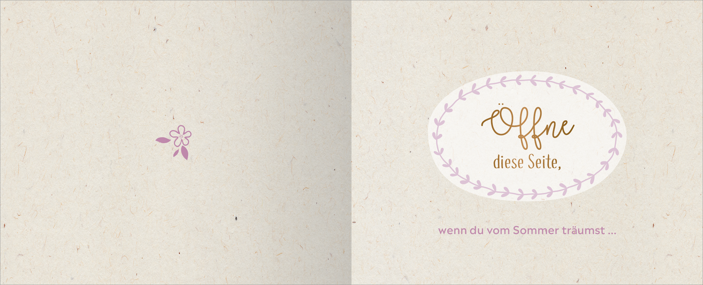 Gezeigt wird eine Innen- oder Zusatzansicht von „Happy Birthday – Alles Gute!“. Die linke Seite zeigt eine dezent gestaltete, helle Fläche mit einem kleinen, pinken Blütenmotiv. Auf der rechten Seite befindet sich ein ovaler Rahmen, umrandet von einem zarten, lilafarbenen Lorbeerkranz. Innen steht der Text „Öffne diese Seite,“ in geschwungener, goldener Schrift, darunter „wenn du vom Sommer träumst ...“ in schlichter, rosafarbener Typografie.