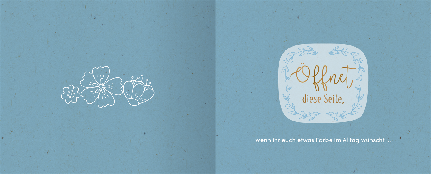 Gezeigt wird eine Innen- oder Zusatzansicht von „Zur goldenen Hochzeit – 50 Jahre Glück und Liebe“. Die Seite präsentiert eine sanfte, himmelblaue Hintergrundfarbe, verziert mit feinen, weißen Blumenillustrationen auf der linken Seite. Auf der rechten Seite befindet sich ein geschwungenes Textfeld mit der Aufschrift „Offnet diese Seite“ in eleganter goldener Schrift, umgeben von einer zarten, hellblauen Umrandung. Darunter steht in schlichter weißer Schrift der Satz „wenn ihr...
