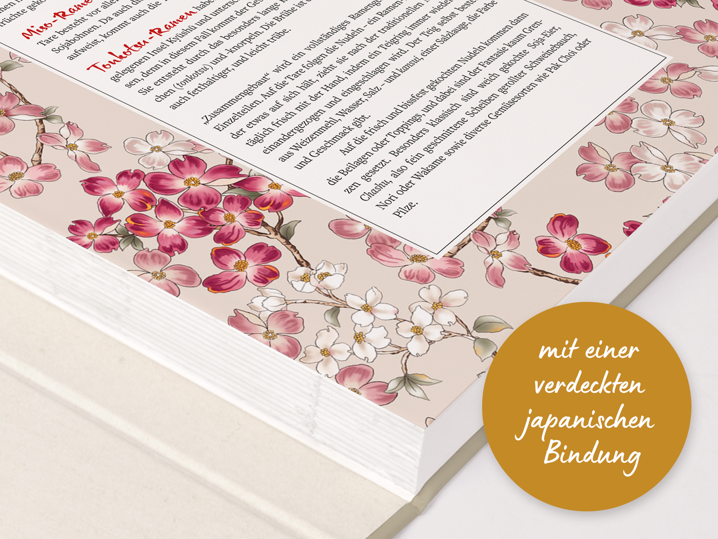 Gezeigt wird eine Innen- oder Zusatzansicht von „Sehnsucht nach Japan“. Die Illustration zeigt zarte Blüten in Rosa und Weiß, die sich harmonisch über einen sanften, cremefarbenen Hintergrund erstrecken. Im oberen Bereich befindet sich ein Info-Text in schwarzer, klarer Schrift, eingerahmt von floralen Mustern. Ein goldener Plaketten-ähnlicher Kreis zeigt den Hinweis auf die versteckte japanische Bindung. Die Farbgebung und Typografie vermitteln eine elegante und einladende Atmosphäre.