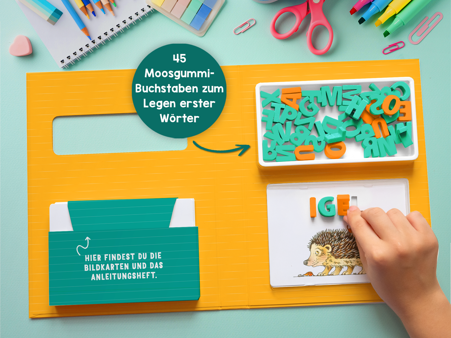Gezeigt wird eine Innen- oder Zusatzansicht von „Zum Schulstart – Buchstaben und Wörter legen“. Die Ansicht zeigt eine helle, farbenfrohe Tischoberfläche in Blau und Gelb. Auf der rechten Seite liegt ein Arbeitsblatt mit einem Igel und dem Wort „IGEL“ in bunten Buchstaben. Linkerhand sind ein Stapel Bildkarten sowie ein Anleitungsheft sichtbar. Darüber befindet sich eine Box mit 45 Moosgummibuchstaben in verschiedenen Farben, die zum Legen erster Wörter einladen. Alle Elemente...