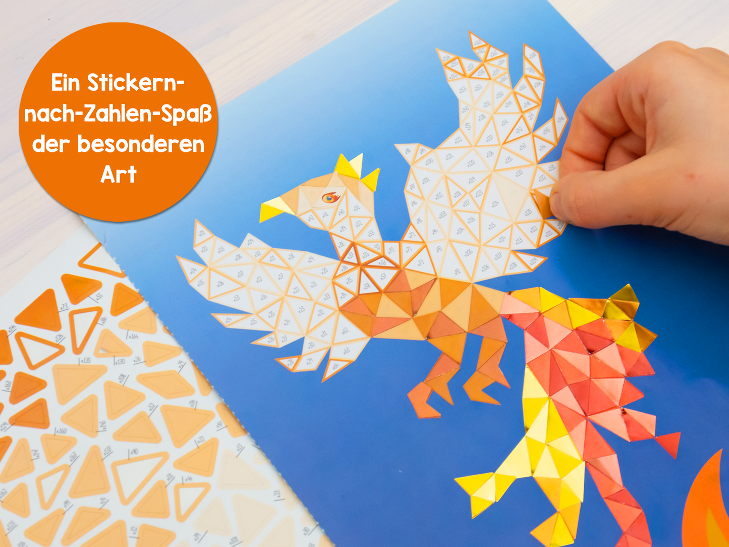 Gezeigt wird eine Innen- oder Zusatzansicht von „I Love to Sparkle – Mosaik-Stickerheft Fabelwesen“. Auf einem blauen Hintergrund erhebt sich ein farbenfroher Phoenix aus orange- und gelbtönen Mosaikfragmenten, die in geometrischen Formen angeordnet sind. Eine Hand platziert vorsichtig einen Sticker, während auf der linken Seite die nummerierten Sticker-Designs sichtbar sind. Der Titel des Hefts wird in einem spielerischen Orange hervorgehoben.
