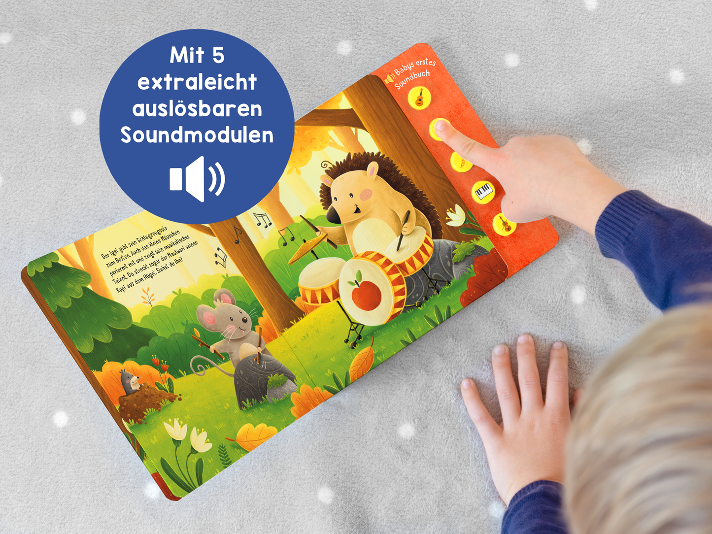 Gezeigt wird eine Innen- oder Zusatzansicht von „Hör mal, so klingt die Musik!“. Auf der linken Seite sind farbenfrohe Illustrationen von Tieren im Wald, darunter eine Maus und ein Igel, die musizieren. Rechts sind fünf große, farbige Druckknöpfe zur einfachen Nutzung platziert. Der Hintergrund ist grün mit Bäumen und bunten Blumen. Ein blauer Kreis mit weißer Schrift hebt die Funktion der „5 extraleicht auslösbaren Soundmodulen“ hervor.