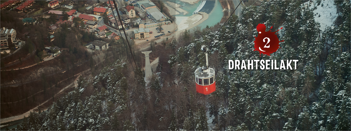 Gezeigt wird eine Innen- oder Zusatzansicht von „Tod mit Talblick“. Die Aufnahme zeigt eine schneebedeckte Landschaft mit einer roten Gondel, die zwischen Bäumen hängt. Im Hintergrund sind Gebäudestrukturen und ein Fluss sichtbar. Im oberen Bereich steht die Zahl „2“ in einem roten angemuteten Blutfleck, begleitet von einem blutigen Spritzereffekt. Darunter befindet sich die Kapitelüberschrift "DRAHTSEILAKT" in klarer, weißer Schrift, die gut lesbar ist.