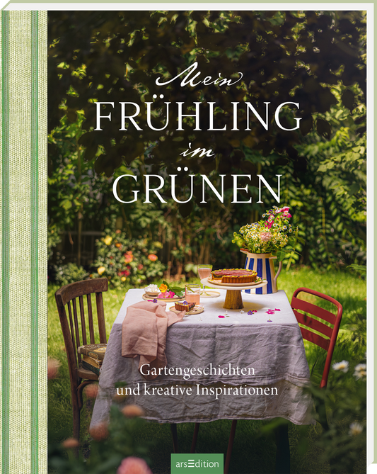 Das Cover zeigt einen einladenden Gartentisch unter grünen Bäumen, gedeckt mit einer weißen Tischdecke und buntem Geschirr. Auf dem Tisch stehen eine Vase mit frischen Blumen und leckere Kuchen. In elegantem Weiß prangt der Titel „Mein FRÜHLING im GRÜNEN“ auf einem sanften, natürlichen Hintergrund. Darunter sind die Worte „Gartengeschichten und kreative Inspirationen“ in kleinerer, dunklerer Schrift. Ganz unten mittig steht der Logoschriftzug von arsEdition.