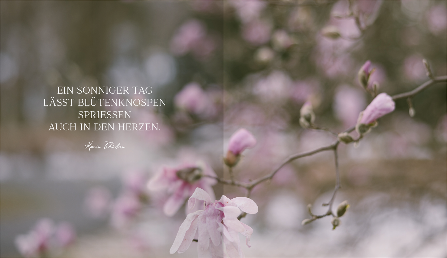 Gezeigt wird eine Innen- oder Zusatzansicht von „Der Geschmack von Frühling“. Die Darstellung umfasst sanfte Pastellfarben, insbesondere ein zartes Rosa der Blüten. Im Hintergrund sind verschwommene grüne und braune Töne zu erkennen, die eine frühlingshafte Atmosphäre schaffen. Der Text in eleganter, geschwungener Schrift lautet: „Ein sonniger Tag lässt Blütenknospen sprießen auch in den Herzen.“ Die Typografie ist ansprechend und harmonisch in das Bild integriert.