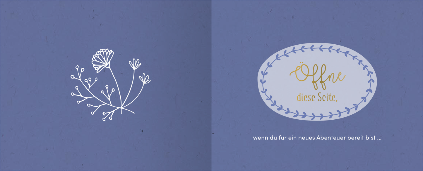 Gezeigt wird eine Innen- oder Zusatzansicht von „Alles Liebe zum Jahrestag“. Die linksseitige Innenseite präsentiert eine filigrane, weiße Blumenillustration auf einem sanften, blauen Hintergrund. Die rechtsseitige Fläche enthält einen ovalen Rahmen mit der einladenden Aufschrift „Offne diese Seite“ in kräftigem Gold und einer klaren Schriftart. Darunter steht in kleinerer, weißer Schrift der Satz „wenn du für ein neues Abenteuer bereit bist ...“, was ein Gefühl von...