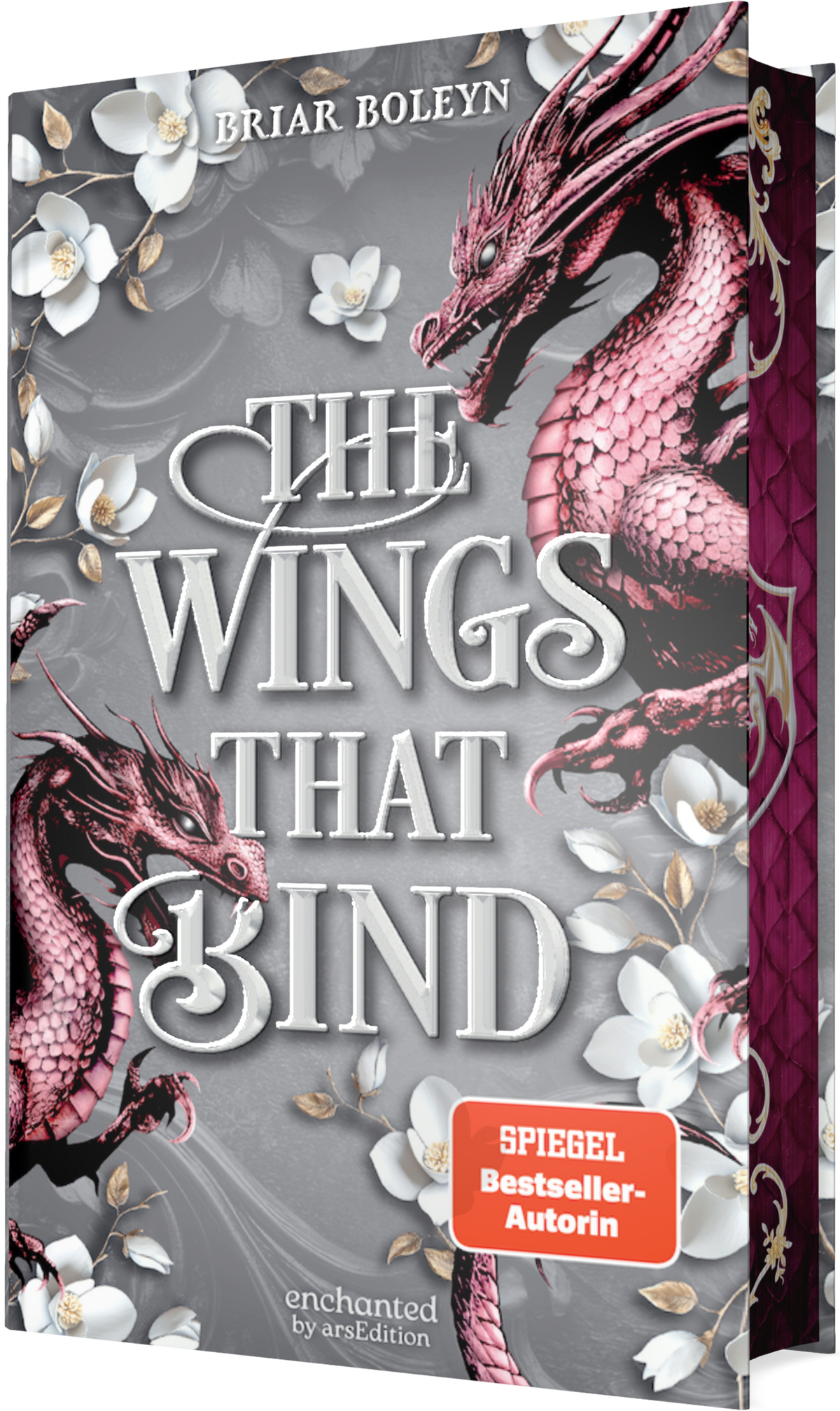 Grauer, ornamentaler Hintergrund, großformatiger weißer Serifentitel „THE WINGS THAT BIND“ in Relief, Autorenname Briar Boleyn oben. Zwei glänzend rosa-magenta Drachen umschlingen den Titel, flankiert von weißen Magnolien mit goldenen Staubfäden. Rechts eine burgunderfarbene Buchrückseite mit goldener Zier. Orangefarbener SPIEGEL-Bestseller-Button mit dem Text „SPIEGEL Bestseller-Autorin“. Atmosphäre episch, elegant und leicht düster. Ganz unten mittig steht der Logoschriftzug...