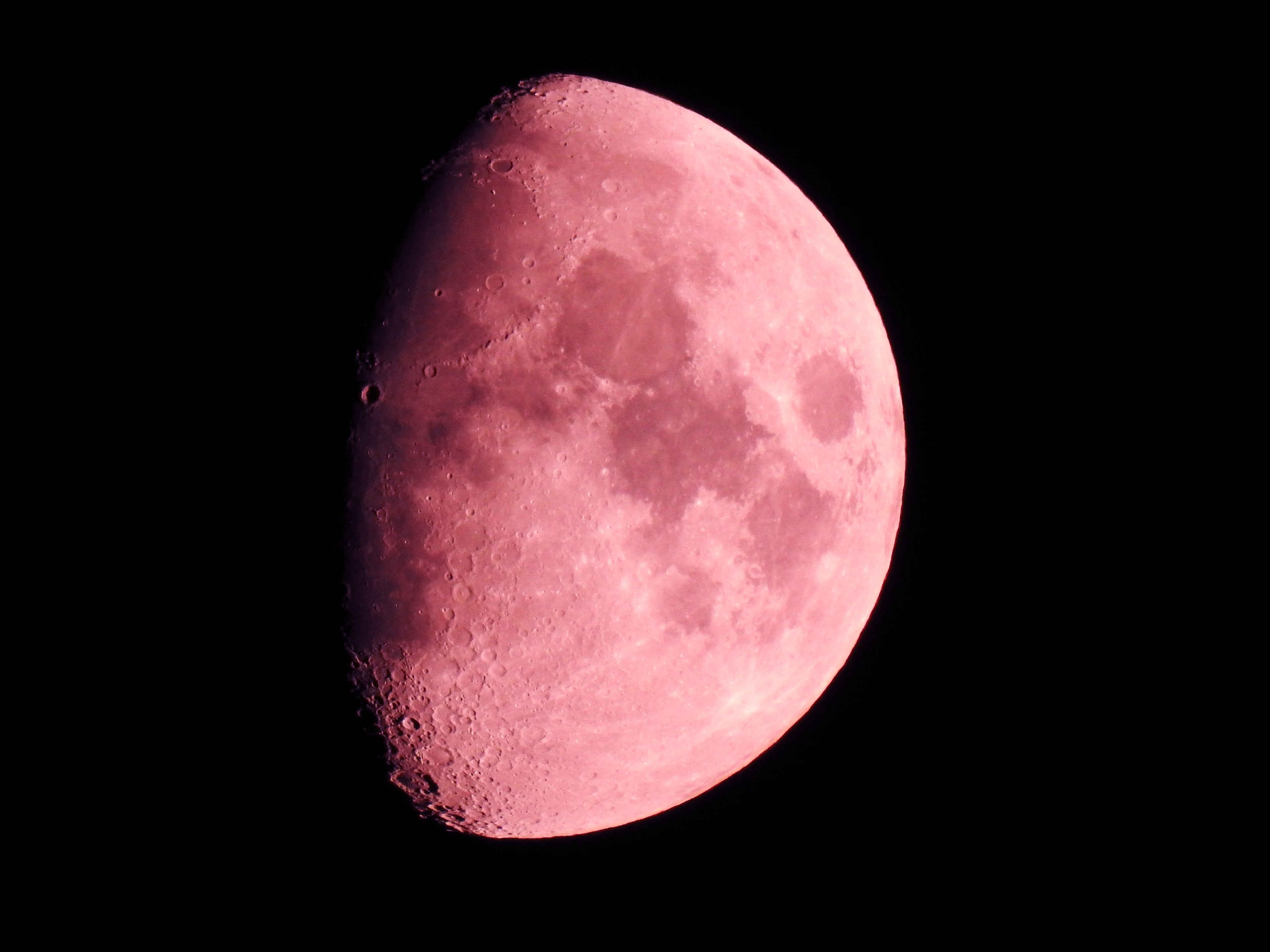 Nahaufnahme des Mondes in einer rosafarbenen Tönung bei Nacht.