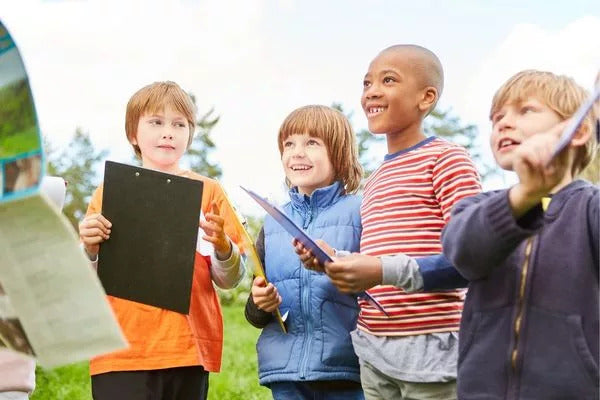 Es sind drei Kinder mit Klemmbrettern zu sehen.