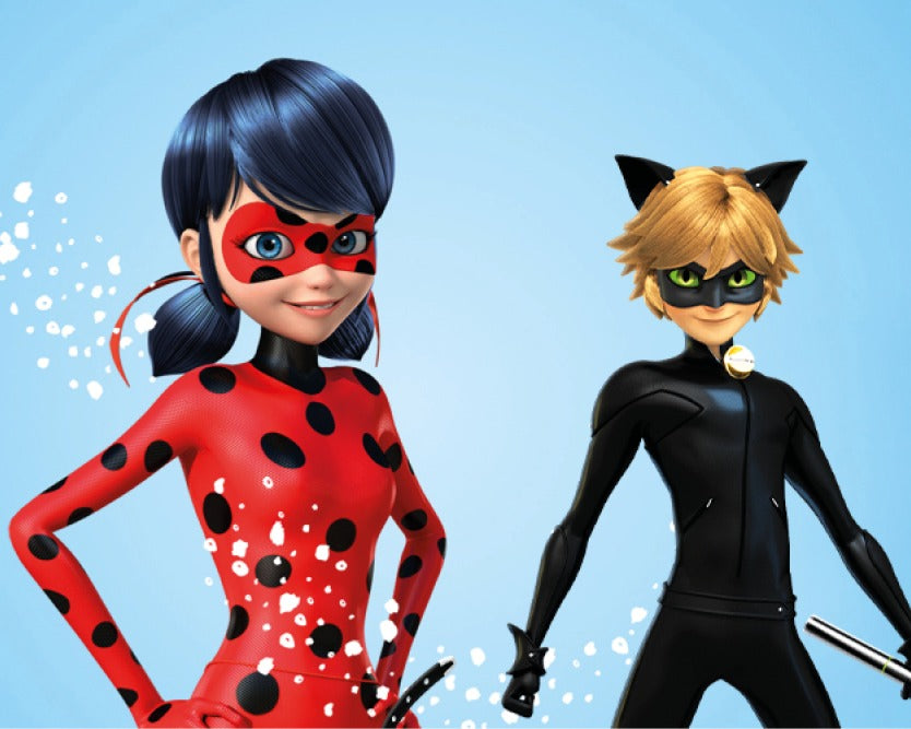 Zwei animierte Charaktere aus der Serie 'Miraculous': Links eine Figur in einem rot-schwarzen Marienkäferkostüm, rechts eine Figur in einem schwarzen Katzenkostüm mit Katzenohren und einem Gürtel mit Glocke. Der Hintergrund ist hellblau mit weißen grafischen Elementen.