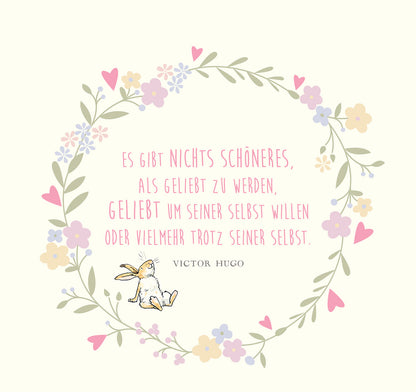 Gezeigt wird eine Innen- oder Zusatzansicht von „Weißt du eigentlich, wie lieb ich dich hab?“. Der Hintergrund ist in einem sanften Creme-Ton gehalten. Um den zentralen Text, der in einer verschnörkelten pinken Schrift präsentiert wird, ist ein zarter, floraler Rahmen aus bunten Blumen und Herzen angeordnet. Am unteren Rand sitzt ein niedlicher, gezeichneter Hase. Der Gesamteindruck ist freundlich und verspielt.