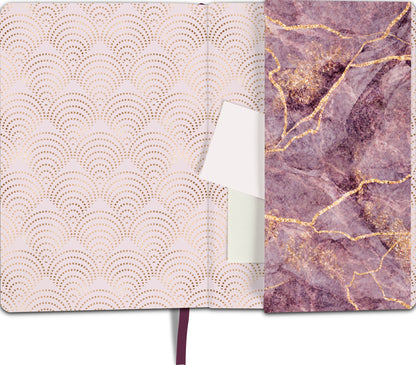 Gezeigt wird eine Innen- oder Zusatzansicht von „myNOTES Notizbuch A5: Gedankenmalerei“. Das Innere präsentiert sich in sanften Rosa- und Goldtönen mit einem wellenartigen Muster, das an asiatische Designs erinnert. Auf der rechten Seite ist eine strukturierte Oberfläche in lila mit goldenen Aderungen zu sehen, die einen eleganten und modernen Eindruck vermittelt. Das Notizbuch enthält ein Fach für Notizen oder Karten und einen lila Leseband als praktisches Detail.