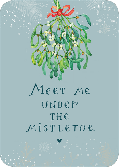 Gezeigt wird eine Innen- oder Zusatzansicht von „Weihnachtspost für dich und mich“. Die Postkarte hat einen zarten, hellblauen Hintergrund und zeigt mistelartige Pflanzen mit grünen Blättern und weißen Beeren. Oben ist eine rote Schleife angebracht. In elegant geschwungener Schrift steht der Text „Meet me under the mistletoe“ in dunklerem Blau, gefolgt von einem kleinen Herzen. Die Gesamtgestaltung vermittelt ein festliches, einladendes Gefühl.