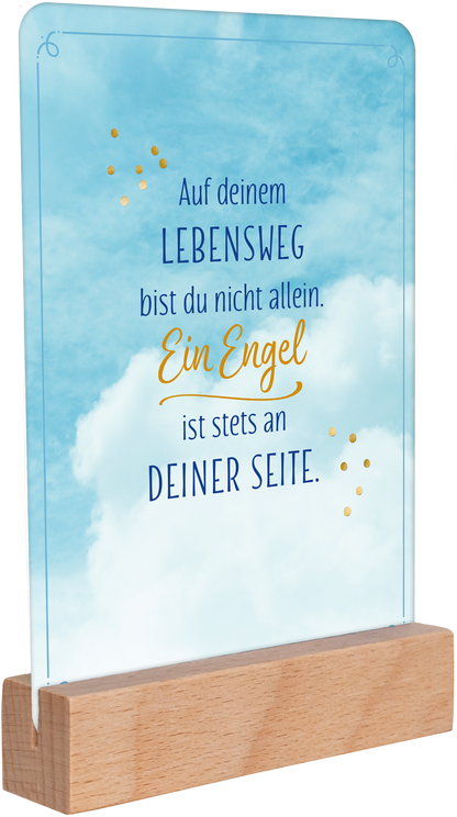 Gezeigt wird eine Innen- oder Zusatzansicht von „Ein Engel für jeden Tag“. Der Hintergrund zeigt einen sanften blauen Himmel mit Wolken. In einer harmonischen Kombination aus Blau und Gelb ist der Schriftzug platziert: „Auf deinem LEBENSWEG bist du nicht allein. Ein Engel ist stets an DEINER SEITE.“ Die Typografie wirkt freundlichen mit unterschiedlichen Schriftgrößen und einer eleganten, geschwungenen Note im Wort „Engel“. Ein schlichtes Holzstandfuß ergänzt das gefühlvolle...