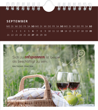 Gezeigt wird eine Innen- oder Zusatzansicht von „Wandkalender Gartenglück 2026“. Der Kalender zeigt den Monat September mit einer Grafikeinlage, die ein Picknick-Setting darstellt. Im Vordergrund sind ein geflochtener Korb und zwei Weingläser abgebildet. Der Hintergrund ist grün mit blühenden Blumen. Über dem Bild steht der Quote „Sich zu entspannen ist besser, als beschäftigt zu sein“ in eleganter, geschwungener Schrift, gefolgt von der Autorenangabe in schlichter Typografie. Der...