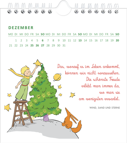 Gezeigt wird eine Innen- oder Zusatzansicht von „Wandkalender Man sieht nur mit dem Herzen gut 2026“. Der Dezember zeigt einen bunten, illustrierten Kalenderblatt mit einem fröhlichen kleinen Prinzen in grüner Kleidung, der auf einer Leiter steht und einen Weihnachtsstern auf einen Tannenbaum setzt. Ein roter Fuchs sitzt am Boden. Die Monatsüberschrift und die Wochentage sind in frischem Grün gehalten, während der Text in lebhaftem Rot auf weißem Hintergrund erscheint.