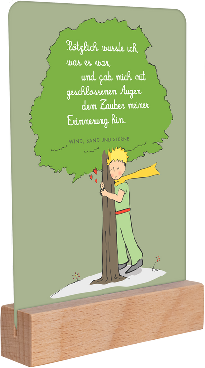 Gezeigt wird eine Innen- oder Zusatzansicht von „Der Kleine Prinz. Geburtstagskalender“. Die Abbildung zeigt eine stilisierte Szene mit einem kleinen Prinzen, der an einem Baum lehnt. Der Hintergrund ist in sanftem Grün gehalten. Über dem Prinzen steht ein Zitat in eleganter, geschwungener Schrift, die in Weiß gehalten ist. Der Prinz trägt ein grünes Outfit mit einem roten Gürtel und eine gelbe Schärpe. Unterhalb des Baumes sind Herzen und das Zitat „WIND, SAND UND STERNE“ zu...
