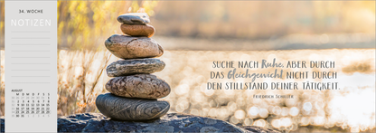 Gezeigt wird eine Innen- oder Zusatzansicht von „Tischkalender Einatmen. Ausatmen. Lächeln. 2027“. Im Bild sind gestapelte Steine vor einem verschwommenen, natürlichen Hintergrund zu sehen. Auf der rechten Seite steht in geschwungener Schrift: „SUCHE NACH RUHE, ABER DURCH DAS GLEICHGEWICHT NICHT DURCH DEN STILLSTAND DEINER TÄTIGKEIT.“ Darunter befindet sich der Name des Zitatgebers, Friedrich Schiller. Die Farbpalette ist warm und beruhigend, mit Erdtönen und sanften...