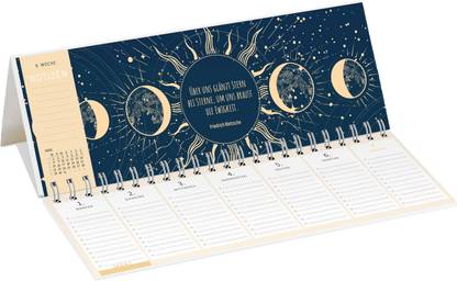 Gezeigt wird eine Innen- oder Zusatzansicht von „Tischkalender Mein magisches Jahr 2027“. Die Darstellung zeigt einen dunklen Hintergrund in einem tiefen Blau, überzogen mit goldenen Elementen und Mondphasen. In der Mitte steht ein Zitat von Friedrich Nietzsche, umgeben von strahlenförmigen Verzierungen. Der Kalender bietet eine klare Struktur mit weißen, beschriftbaren Zeilen für jede Woche, die durch dezente Linien voneinander getrennt sind. Links sind Notizen und ein kleines...