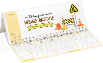 Gezeigt wird eine Innenansicht von „Tischkalender Nie ist der Freitag da, wenn man ihn braucht! 2027“. Der Kalender zeigt eine helle, freundliche Gestaltung in Weiß und Gelb. Oben steht der Text „Ich bin gerade eine MENTALE-BAUSTELLE“ in einer verspielten Schriftart. Darunter befinden sich bunte Baustelle-Illustrationen wie Helme und Pylonen. Die Wochentage sind klar strukturiert, mit ausreichend Platz für Notizen, und heben sich durch eine klare Typografie ab.