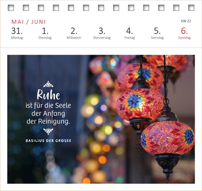 Gezeigt wird eine Innen- oder Zusatzansicht von „Postkartenkalender Innere Stärke 2027“. Die Ansicht zeigt den Monat Mai/Juni mit der Datumsangabe für die ersten Juni-Tage. Im Hintergrund sind farbenfrohe, leuchtende Laternen zu sehen, die in warmen Rottönen und sanften Gelbtönen strahlen. In der linken unteren Ecke steht der Spruch „Ruhe ist für die Seele der Anfang der Reinigung.“ in eleganter, geschwungener Schrift. Darunter ist „Basilus der Große“ in einer schlichteren...