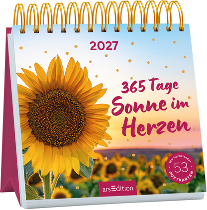 Spiralaufsteller mit großem gelbem Sonnenblumenmotiv links vor einem warmen Sonnenuntergangsverlauf von Hellblau über Rosa zu Orange. Oben mittig steht „2027“ in klarer serifenloser Schrift, rechts daneben prominent in handschriftlicher magentafarbener Schriftzug „365 Tage Sonne im Herzen“. Goldene Pünktchen und ein runder magentafarbener Badge mit „Wochenkalender 53 Postkarten“ ergänzen die Gestaltung. Ganz unten mittig steht der Logoschriftzug von arsEdition.