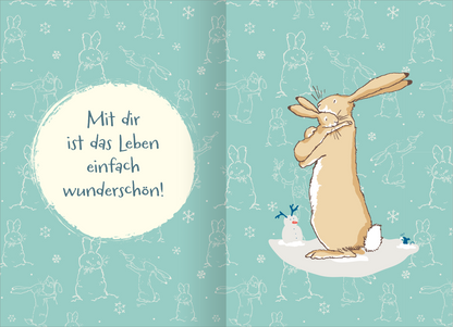 Gezeigt wird eine Innen- oder Zusatzansicht von „Buchkalender Weißt du eigentlich, wie lieb ich dich hab? 2027“. Die Seite zeigt einen hellblauen Hintergrund, auf dem in leichtem, skizzenhaften Stil Hasenabdrücke und Schneeflocken zu sehen sind. In der Mitte steht in einem cremefarbenen, runden Feld der Text „Mit dir ist das Leben einfach wunderschön!“. Der dazugehörige, braun-beige gezeichnete Hase wirkt nachdenklich und umarmt sich, während ein kleiner Schneemann rechts von ihm...