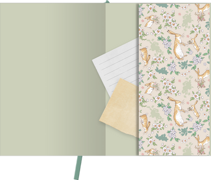 Gezeigt wird eine Innen- oder Zusatzansicht von „myNOTES Papeterie: Weißt du eigentlich, wie lieb ich dich hab? Notizbuch A5“. Die Innenseiten sind in sanften Grüntönen gehalten, ergänzt durch ein zartes, florales Muster mit niedlichen Hasen. Auf der linken Seite befindet sich ein liniertes Notizblatt und ein kleines, beiges Papierstück. Die Typografie ist freundlich und gut lesbar, was eine einladende und kreative Atmosphäre schafft.