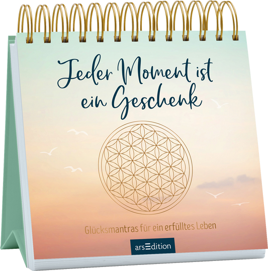 Das Buchcover zeigt eine sanfte Farbverlauf, der von einem hellen Türkis über ein zartes Rosa bis zu einem sanften Beige übergeht. In der Mitte steht in geschwungener blauer Schrift der Titel „Jeder Moment ist ein Geschenk“. Darunter befindet sich der Untertitel „Glücksmantras für ein erfülltes Leben“ in einer klaren, serifenlosen Schrift. Ein stilisiertes, kreisförmiges Motiv, das die „Blume des Lebens“ darstellt, ergänzt das Design. Ganz unten mittig steht der...