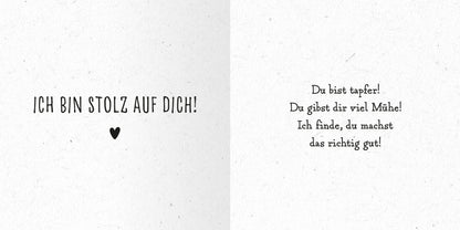 Gezeigt wird eine Innen- oder Zusatzansicht von „Das kleine Alles-wird-gut-Buch“. Auf der linken Seite steht in großer, schwarzer Schrift der Text „ICH BIN STOLZ AUF DICH!“ über einem kleinen Herzen. Die rechte Seite zeigt in einer verspielten, handschriftlichen Typografie die Ermutigung „Du bist tapfer! Du gibst dir viel Mühe! Ich finde, du machst das richtig gut!“. Der Hintergrund ist in einem sanften, hellen Farbton gehalten, was eine freundliche und einladende Atmosphäre...