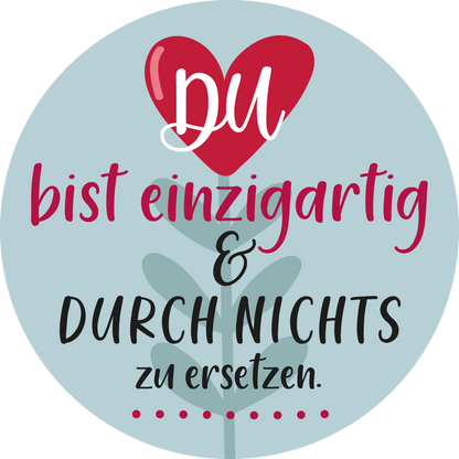 Gezeigt wird eine Innen- oder Zusatzansicht von „Beste Mama von allen“. Der Hintergrund ist hellblau und trägt einen roten stilisierten Herz-Icon. In verspielter Schrift steht „DU“ in Weiß und Rot über dem Text „bist einzigartig &amp;“ in einem kräftigen Violett. Darunter folgt „DURCH NICHTS“ in schwarzer Blockschrift, gefolgt von „zu ersetzen“ in einer eleganten, schwungvollen Typografie. Eine graue Blattform unterstreicht die Botschaft.