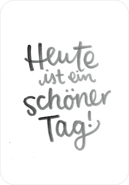 Gezeigt wird eine Innen- oder Zusatzansicht von „Glücksmantras für die Handtasche“. Der Hintergrund ist weiß, darauf befindet sich die handschriftlich gestaltete Aufschrift „Heute ist ein schöner Tag!“ in verschiedenen Grautönen. Die Schriftarten variieren zwischen luftig und geschwungen für den Satzteil „schöner Tag!“, der mit einer verspielten Unterlinie versehen ist. Die Verwendung von lockeren, dynamischen Linien sorgt für eine positive, motivierende Ausstrahlung.