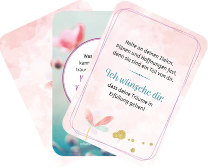 Gezeigt wird eine Innen- oder Zusatzansicht von „Ich wünsch dir was“. Die Karten präsentieren sanfte, pastellfarbene Hintergründe in Rosa und Grün. Die Typografie ist klar und gut lesbar, mit einer Mischung aus verspielten und eleganten Schriftarten. Auf einer Karte steht der Wunsch „Ich wünsche dir, dass deine Träume in Erfüllung gehen!“ in auffälligem Blau. Dekorative Blumenmotive und goldene Akzente ergänzen das harmonische Design.