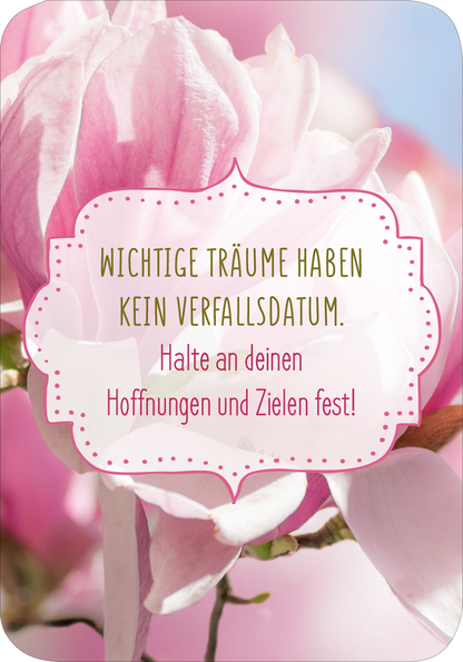 Gezeigt wird eine Innen- oder Zusatzansicht von „Glückskärtchen für Alltagsheldinnen“. Das Kärtchen zeigt eine sanfte, verschwommene Fotografie von rosa Blüten auf einem hellen Hintergrund. Darauf ist ein dekorativer, geschwungener Rahmen in Hellrosa zu sehen. In der Mitte steht der Spruch „Wichtige Träume haben kein Verfallsdatum.“ in einer eleganten, goldenen Schrift. Darüber befindet sich der Zusatz „Halte an deinen Hoffnungen und Zielen fest!“, ausgesprochen einladend und...