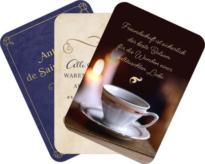 Gezeigt wird eine Innen- oder Zusatzansicht von „Kleine Literaturapotheke“. Die Abbildung zeigt drei Karten in unterschiedlichen Farben: eine dunkle blaue Karte mit goldenen Verzierungen und dem Text „An de Saint...“, eine cremefarbene Karte mit „Alle waren einmal...“ in eleganter Schrift sowie eine dritte Karte mit einem klaren, warmen Hintergrund und einer Tasse, auf der steht: „Freundschaft ist sicherlich der beste Balsam für die Wunden einer entzauberten Liebe“. Die...