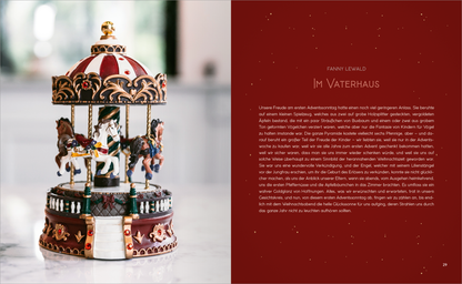 Gezeigt wird eine Innenansicht von „Weihnachten“. Auf der linken Seite befindet sich ein festlich dekorierter Karussellanhänger mit mehreren weißen Pferden, die auf einem runden, kunstvoll verzierten Sockel stehen. Die Farben sind warm und einladend, mit tiefen Rottönen und goldenen Akzenten. Auf der rechten Seite ist der Text „Im Vaterhaus“ in eleganter, serifenbetonter Typografie dargestellt, umrahmt von einer angenehmen, winterlichen Szenerie.