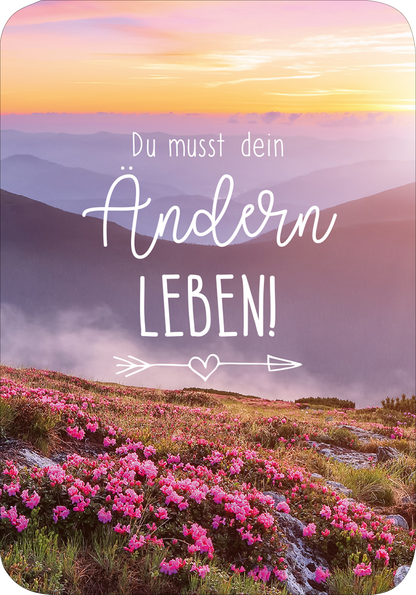 Gezeigt wird eine Innen- oder Zusatzansicht von „Einatmen und Ausrasten“. Die Gestaltung zeigt eine malerische Berglandschaft mit sanften, pastelartigen Farben im Hintergrund, die von einem weichen Sonnenuntergang erhellt wird. Im Vordergrund blühen lila und pinkfarbene Rhododendren. Der Text in einer verspielten Schriftart verkündet „Du musst dein Ändern LEBEN!“ in weißen Buchstaben, begleitet von dekorativen Elementen wie Pfeilen und einem Herz.
