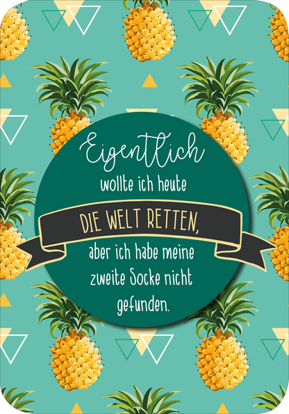 Gezeigt wird eine Innen- oder Zusatzansicht von „Einatmen und Ausrasten“. Die Illustration zeigt einen bunten Hintergrund in Türkis, der mit leuchtend gelben Ananas und geometrischen, weißen Dreiecken versehen ist. Im Zentrum befindet sich ein runder, grüner Bereich mit der Aufschrift „Eigentlich wollte ich heute DIE WELT RETTEN, aber ich habe meine zweite Socke nicht gefunden“. Die Typografie ist verspielt und variiert in Schriftarten und -größen, während ein schwarzes Banner den...
